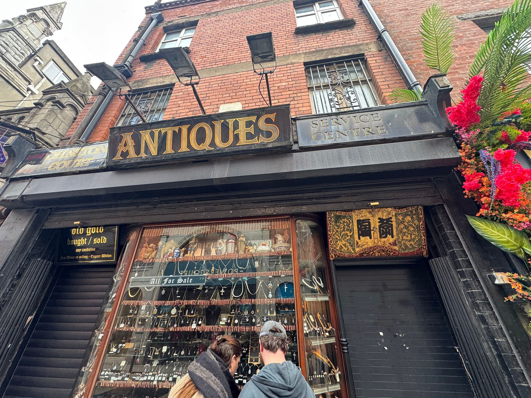 Traditional Dublin city-centre antiques shopfront with black security shutters partially raised over the display windows
