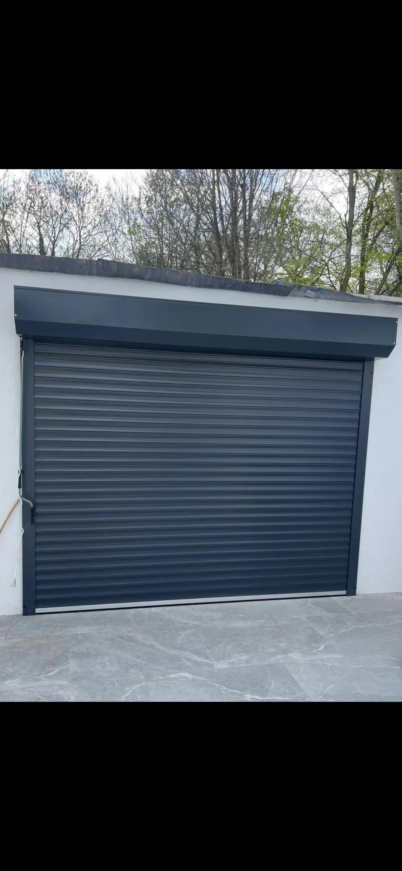 Newly installed anthracite grey insulated roller shutter on a residential garage with a matching boxed headcover